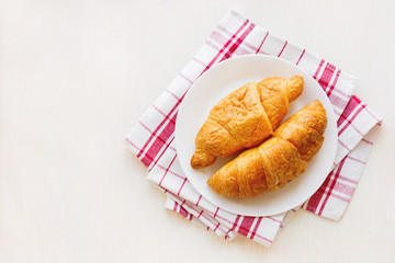 Tasty continental breakfast background - pair of croissants on plaid red napkin. Place for text, top view.