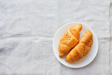 Continental breakfast background - pair of croissants on homespun napkin. Rustic wooden background with place for text. Top view.