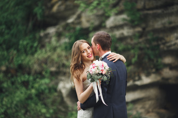 Happy wedding couple hugging and smiling each other on the background gorgeous plants in castle