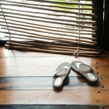 High angle view of slippers on hardwood floor by bamboo blinds