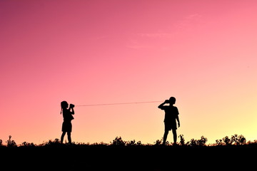 Fototapeta na wymiar Silhouette children playing string phone