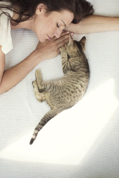 High Angle View Of Woman Sleeping With Cat On Bed At Home