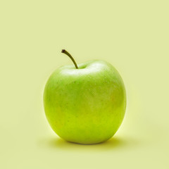 Isolated green apple with a measuring tape on a yellow background