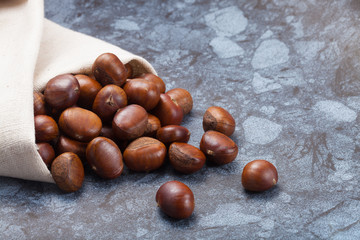 Horizontal image of a pile of chestnuts on stone texture floor with copy space