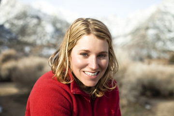 Portrait of smiling woman wearing red sweater in mountains