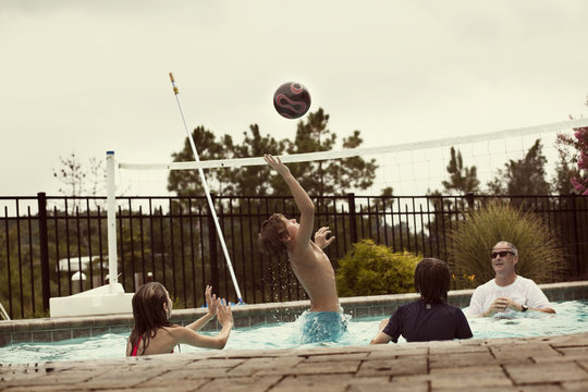 Happy family playing volley ball in pool