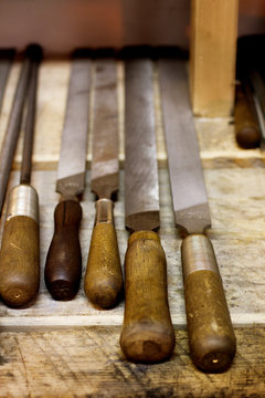 Various chisels on wooden shelf at blacksmith shop