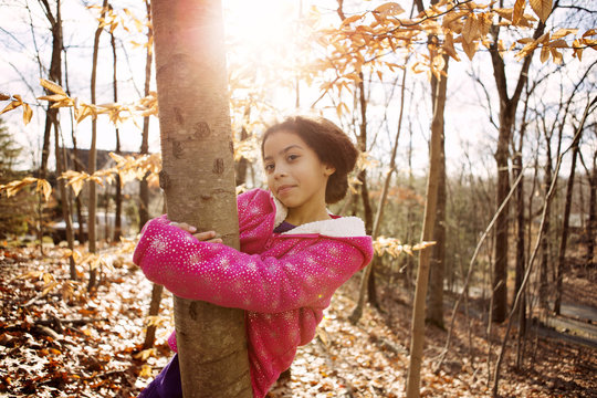 Portrait of girl embracing tree trunk during autumn