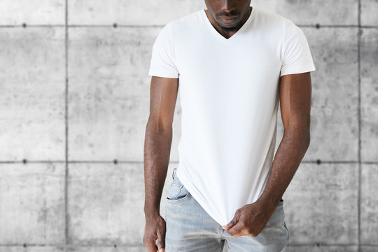 Cropped isolated portrait of athlete African American male model wearing jeans and white blank T-shirt with copy space for your text or promotional content. T-shirt design and advertising concept