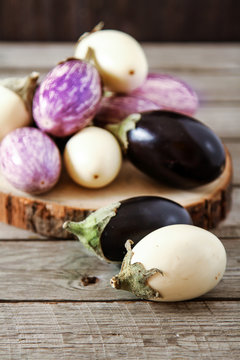 Fresh eggplants of different color on dark wooden background. Ve