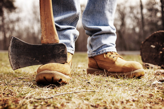 Low section of lumberjack with pick axe on field