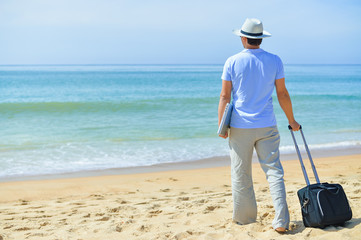 Back view of young businessman with laptop on beach blue sky outdoors background