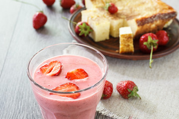 Glass of strawberry smoothie and cheesecake.