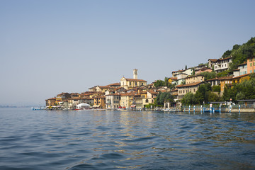 Die bunten Häuser von Peschiera Maraglio schmiegen sich an den bewaldeten Hügel der Monte Isola...