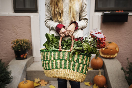 Midsection of woman holding vegetable and flower basket