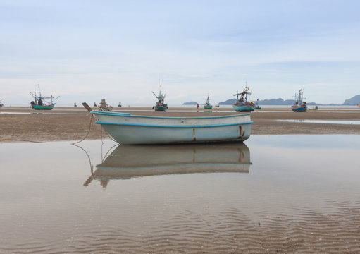 Reflection of fiberglass boat on  low tide beach .