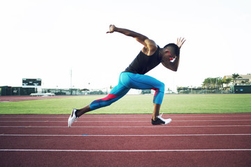 Side view of young athlete running on track