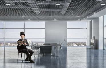 Businessman in cylinder reading book