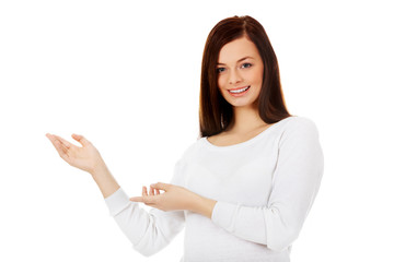 Smiling young woman shows something