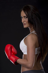 Long dark hair girl on kick box training with red gloves on her hands