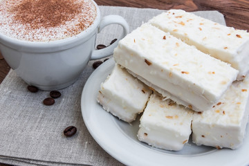 cup of cappuccino with cinnamon and white cakes