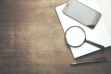 magnifying glass and phone on notebook