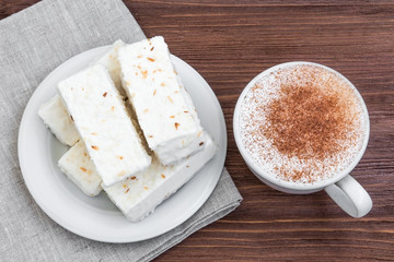 cup of cappuccino with cinnamon and white cakes
