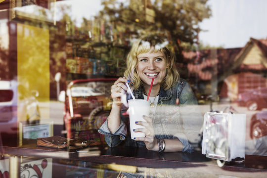 Woman behind window drinking milkshake