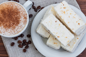 cup of cappuccino with cinnamon and white cakes
