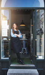 Cheerful barista leaning against doorway in cafe