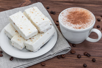cup of cappuccino with cinnamon and white cakes