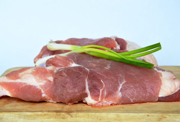 raw pork and spring onion on wooden chop block