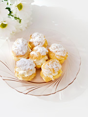 Cream puff or profiterole with filling and powdered sugar topping, isolated, against white background