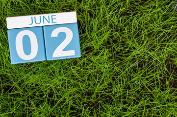 June 2nd. Image of june 2 wooden color calendar on green lawn grass background. Summer day