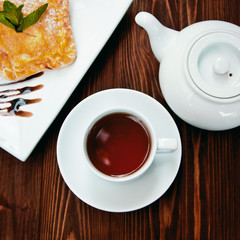 Hot chocolate along with a layer cake with pear and almonds decorated with chocolate and mint leaves