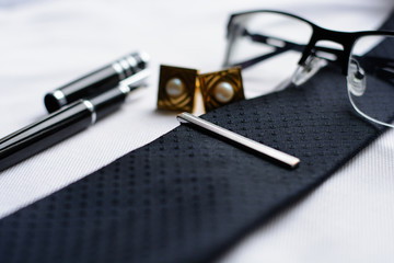 Business accessories (cufflinks, fountain pen, glasses) at the men's classic white shirt with tie