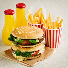 Burger with beef, tomato and herbs. Fries and juice.
