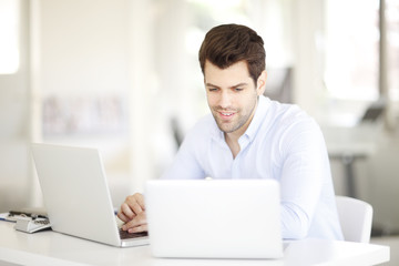Young professional business man working on laptop at office