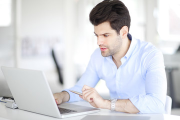 Young professional business man working on laptop at office