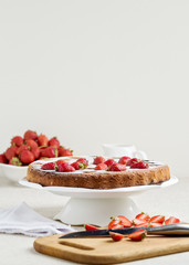 Homemade strawberry cake on a white cake stand.