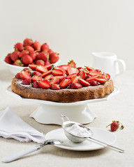 Homemade strawberry cake on a white cake stand.