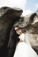 Happy wedding couple kissing and hugging near a high cliff