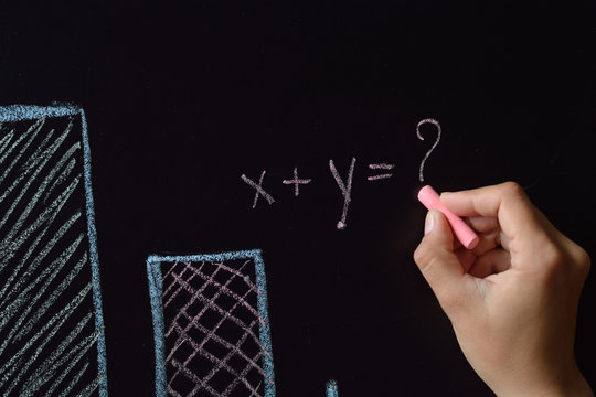 Business woman is drawing charts, plans, diagrams mathematical equation with two unknowns and question mark by colored chalk on a blackboard - Powered by Adobe