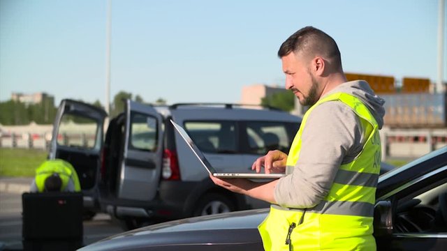 Man in Reflective Safety Vest typing on a laptop on the background of his colleagues