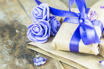 Wrapped gift boxes with presents and decorative flowers on aged wooden background. Place for text.