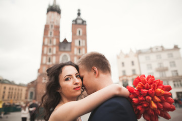 Elegant beautiful wedding couple walking on the main square in Krakow
