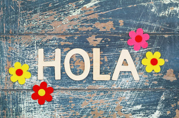 Hola (hello in Spanish) written with wooden letters on rustic surface
