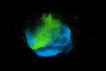 Fototapeta na wymiar Freeze motion of blue and green powder paint exploding isolated on black, dark background. Abstract design of color dust cloud. Particles explosion screen saver, wallpaper brush