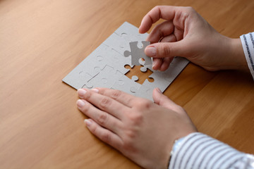 Female hands on a wooden office desk pick puzzle