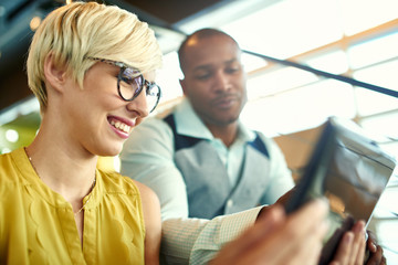 Fototapeta premium Two creative millenial small business owners working on social media strategy using a digital tablet while sitting in staircase
